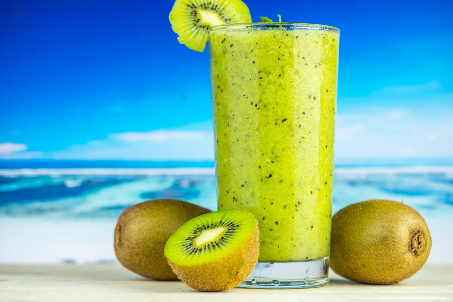 kiwi fruit beside drinking glass filled with kiwi shake